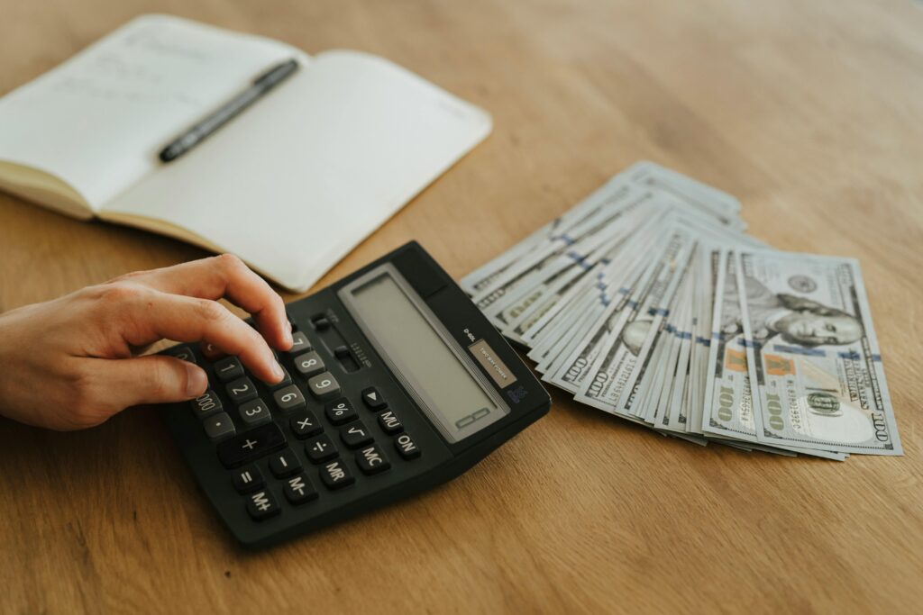 Person using calculator beside money and budget notebook – budgeting concept